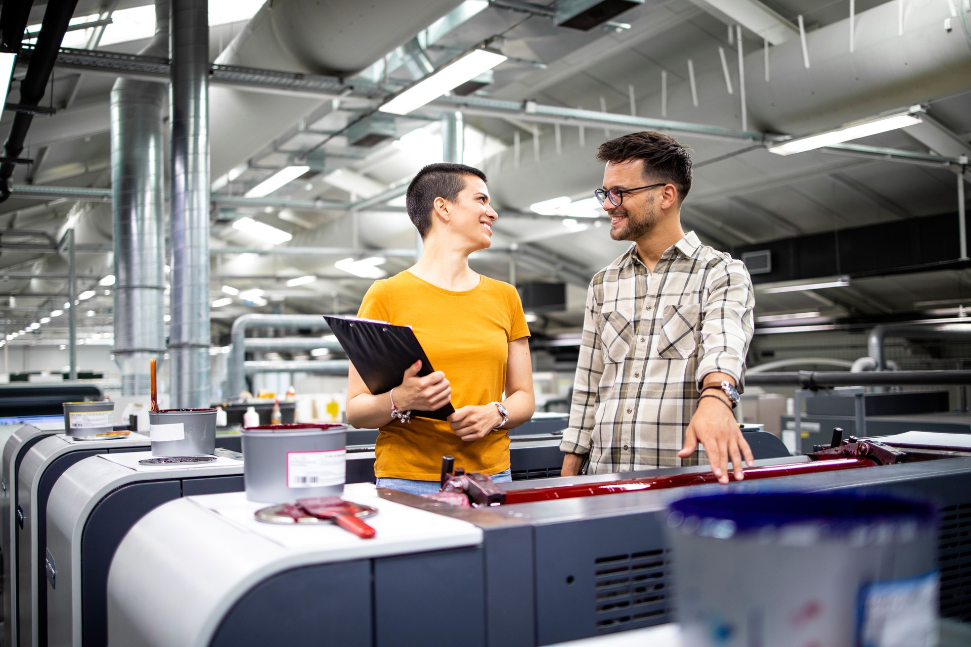 Professional graphic designers or engineers checking color values and controlling process of modern printing machine.